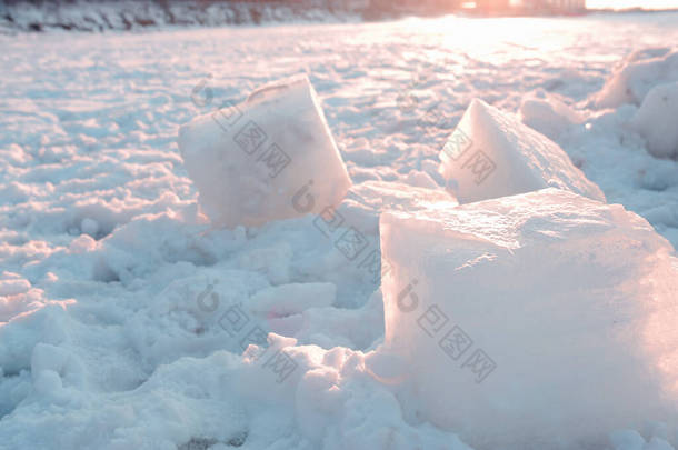 由人类锯成的大冰块躺在雪地上，在冰封的海面上，夕阳西下