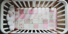 舒适的婴儿床和粉红色的补丁毛毯。儿童保育用床上用品和纺织品。粉红及白色女婴婴儿床照片