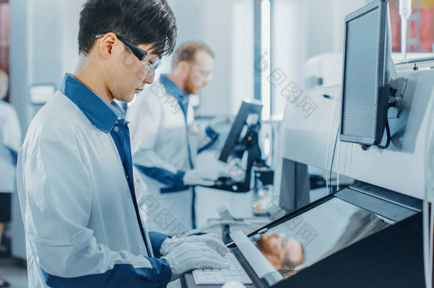 在高科技工厂，亚洲工程师使用计算机编程，为印刷线路板装配线选择和放置电子机械。使用SM机械生产多氯联苯.