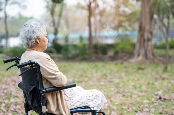 亚洲老年老年妇女患者坐轮椅在公园，健康有力的医疗理念.