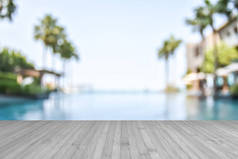 带有蓝色游泳池水和棕榈树的模糊夏季背景热带度假酒店木地板质地