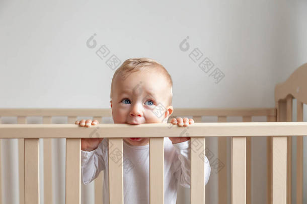 金发可爱的小宝宝咬木制床头板