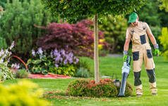 40多岁的白人男子与现代无绳叶吹风清洁他的后院花园.