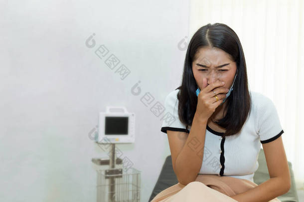 坐在<strong>病床</strong>上出现严重咳嗽症状的亚洲女性患者.