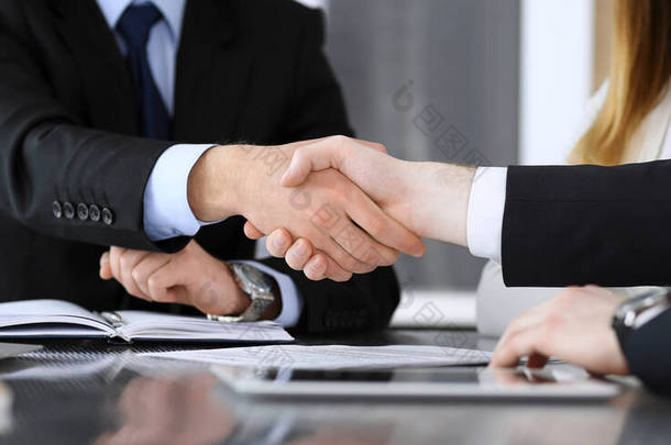 在现代化的办公室里，商人与同事或同事在玻璃桌子上方<strong>握手</strong>，<strong>特写</strong>镜头。不认识的商人在开会。团队精神、伙伴关系和<strong>握手</strong>概念