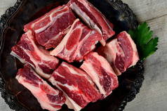 生肉排骨在黑色银盘上,灰色木制背景.生鲜有机牛肉短边