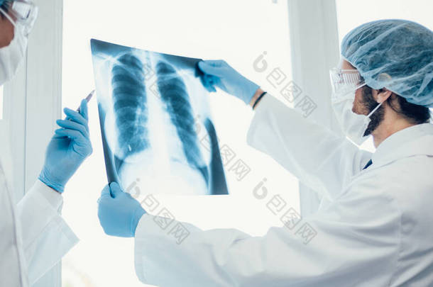 靠近点戴防护面罩的医生讨论<strong>肺部</strong>X光检查 .