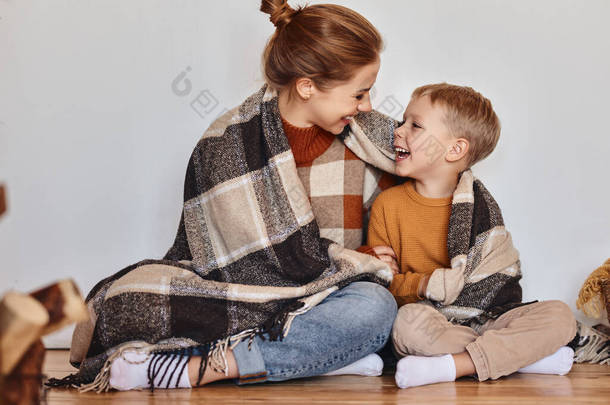 在一个舒适的冬夜，快乐的家庭母亲和可爱的儿子抱在温暖的毛毯里笑着回家