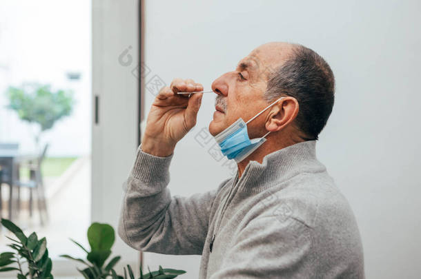 <strong>老年人</strong>坐着，拿着抗原试剂盒在家里做COVID-19的自我测试。结肠炎鼻腔抹片检查是否感染.在线医疗和与<strong>健康</strong>有关的服务.