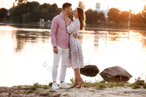 夕阳西下的时候，这对恋人在湖面上互相凝视。美丽的年轻夫妇在夕阳西下，在湖畔漫步，沐浴着灿烂的光芒。复制空间.
