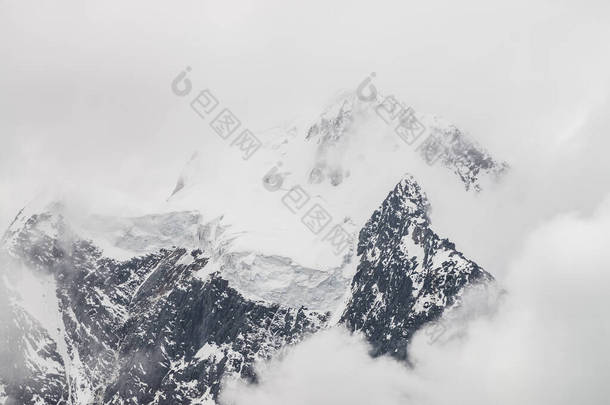 大气极简主义高山景观，在雪山峰顶上挂着巨大的冰川。大阳台上的锯齿状的冰川边缘。雪山间的低云。高空壮丽的风景.