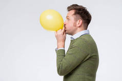 年轻人吹着一个黄色的气球，用它来训练他的肺.