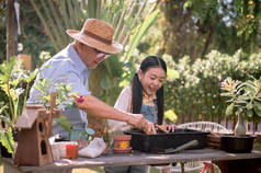 爷爷和孙女在家里的花园里种树.暑假与家人团聚的退休年龄生活方式.