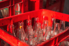 瓶子在一个红色的塑料盒里.空玻璃瓶的颈。碳酸饮料中的玻璃容器