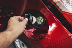 Human hand is open or close fuel tank cap of the red car for refueling