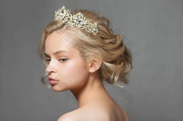 美丽的金发女人，头戴皇冠的新娘的形象。照片是在灰色背景的工作室拍摄的。漂亮的小脸蛋婚礼形象.