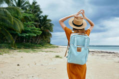 背着背包在海滨棕榈岛旅行的女人