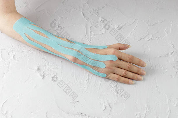 女性手，用弹性运动带制成蓝色医疗补片，在术后和白桌康复期间防止水肿
