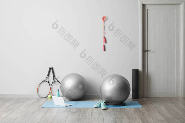 轻墙附近装有健身球和现代笔记本电脑的不同<strong>体育用品</strong>