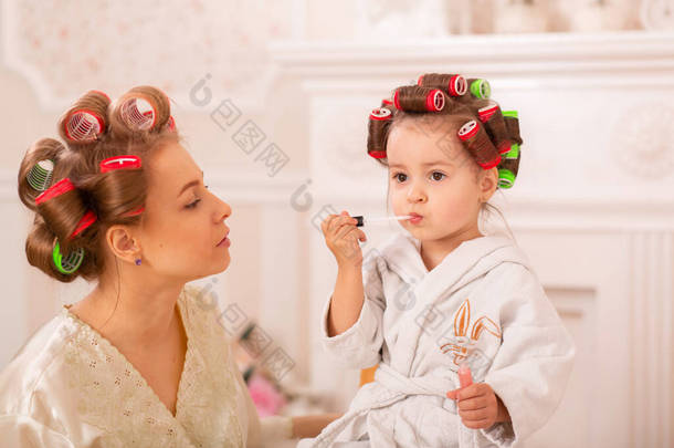 可爱的小<strong>女孩</strong>和她的妈妈在理发刷化妆。妈妈教女儿用化妆品。美丽的一天。<strong>女孩</strong>就是这样的<strong>女孩</strong>.