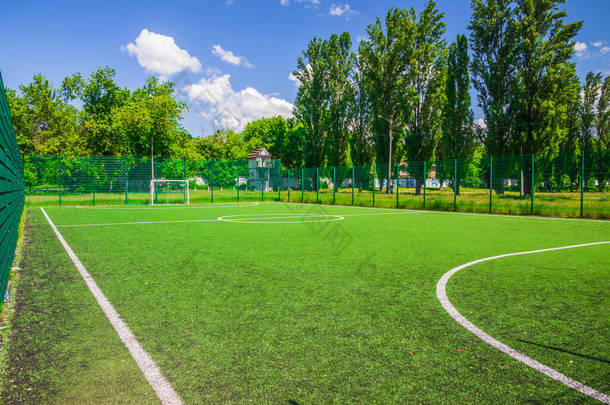 学校附近有人造绿草的足球场。业余足球场。阳光灿烂的夏日