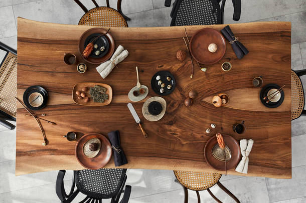 餐厅的室内设计风格<strong>新颖</strong>，有木制核桃木餐桌、复古椅子、餐具、盘子、桌布、茶壶、食品、装饰和典雅的配饰。水泥地面。模板。顶部视图.