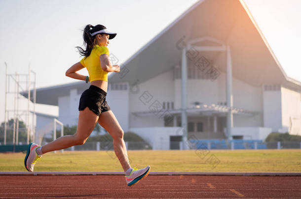 一名年轻的亚洲女<strong>运动</strong>员在阳光灿烂的早晨在城市体育馆的<strong>跑</strong>道上慢<strong>跑</strong>，以保持健康和健康的生活方式。年轻的健身女子在体育场<strong>跑</strong>道上<strong>跑</strong>步.体育和娱<strong>乐</strong>