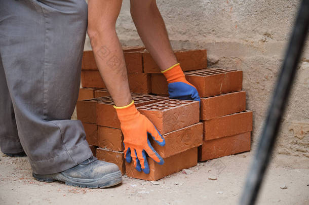 一名年轻的高加索建筑工人在建筑工地搬运砖块.