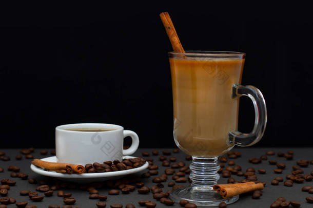 一杯加白咖啡杯的热咖啡。用烤咖啡豆和肉桂棒放在茶托上的杯子。爱尔兰咖啡杯中的牛奶咖啡和洒豆