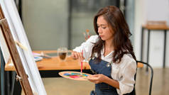 在画架上绘制有才华的亚裔女画家，在工作室、创意职业和业余爱好上保持色彩调色板