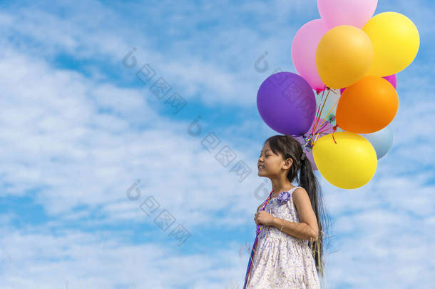 快乐可爱的女孩拿着气球在绿色的草地上快乐地奔跑，白云飘扬，蓝天飘扬。在<strong>生日宴会</strong>上手握着生气勃勃的气球，在室外阳光下欢度夏天
