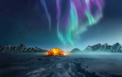夜晚，一个帐篷在雪地里搭成了帐篷，北方的灯光在天空中摇曳。Aurora Borealis和旅行。照片组合.