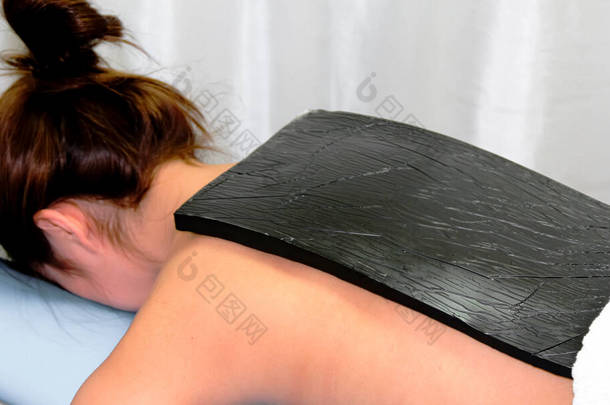 粉红按摩用于粉<strong>红石</strong>蜡压榨。这张照片显示了一位病人在按摩的过程中，带着炽热的风扇压着放松的情景。温泉与健康概念.
