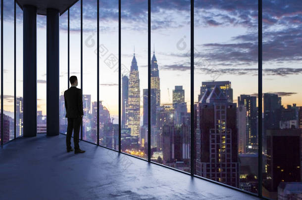在空荡荡的办公室里的商人向窗外望去,城市市区景色明亮.未来、明天、前景和职业概念