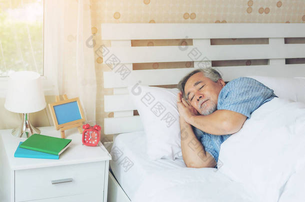 老年男性，老年男性，早上睡在白色卧室的枕头上- -生活方式老年男性健康观念