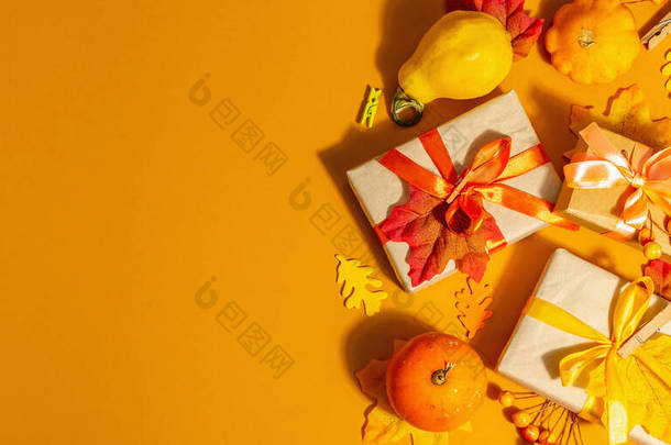 秋色的礼物概念.包装盒,喜庆的秋天装饰,<strong>南瓜</strong>,树叶和浆果.一种时髦的强光，<strong>深色</strong>阴影，橙色背景，横幅格式