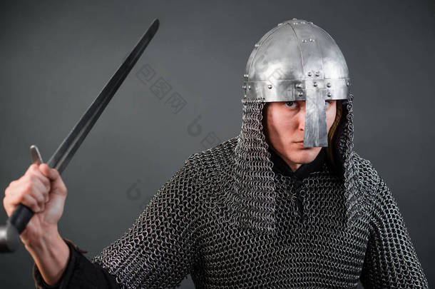 维京时代晚期和十字军东征开始的中世纪战士的画像。戴着锁链的<strong>骑士</strong>，戴着钢盔，带着一把被隔离在黑暗背景下的<strong>剑</strong>.