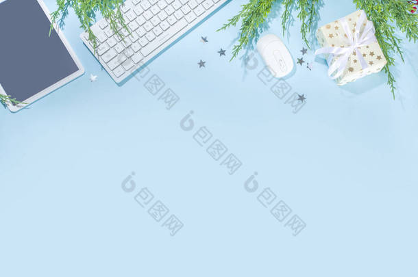 最简单的圣诞办公室背景。现代<strong>浅蓝</strong>色背景，办公室键盘，鼠标，平板电脑，银星和圣诞树枝，平板框
