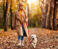 美丽的秋天，一个快乐的微笑的女人在森林里遛狗