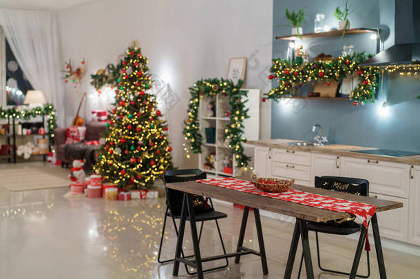 圣诞<strong>家居</strong>装饰有圣诞树和节日<strong>灯</strong>饰，背景厨房装饰节日。圣诞节和新年室内模糊的背景。许多在黑暗中发光的<strong>灯</strong>.