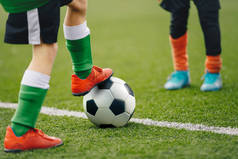 Close up image on soccer player legs with classic ball. Football background of soccer field and play