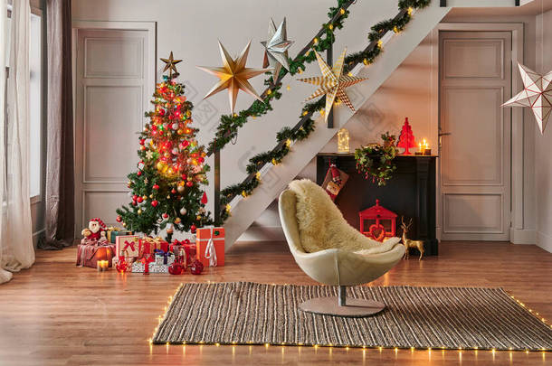 具有松树礼品盒和壁炉、装饰灯、楼梯和门框、灰色墙壁、柳条地毯设计的<strong>现代沙发</strong>圣诞新年理念.