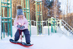 可爱的小女孩学习骑儿童滑雪板，为儿童准备冬季运动，积极运动的安全性