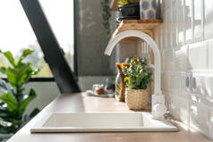 Side view of white sink in contemporary white kitchen interior. Wooden shelves with utensils. Spacio