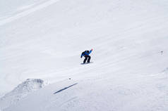 Snowboarder jumping in terrain park at ski resort on sun winter day. Caucasus Mountains, region Domb