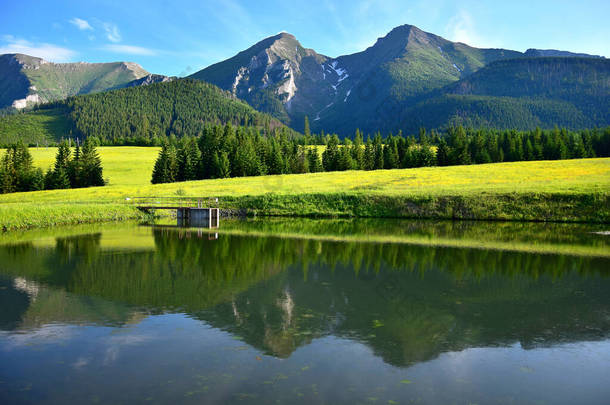 在黄昏的阳光下，相信鞑靼人的两座最高的山，哈弗兰和兹里斯科维亚。前面有一片黄色的花草和一个池塘.