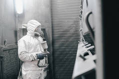 在工厂，员工在工作时穿着化学防护服。喷漆.
