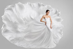 穿白色婚纱的女人《长生不老》中的时尚新娘模型随风飘扬.灰色背景。侧视图.