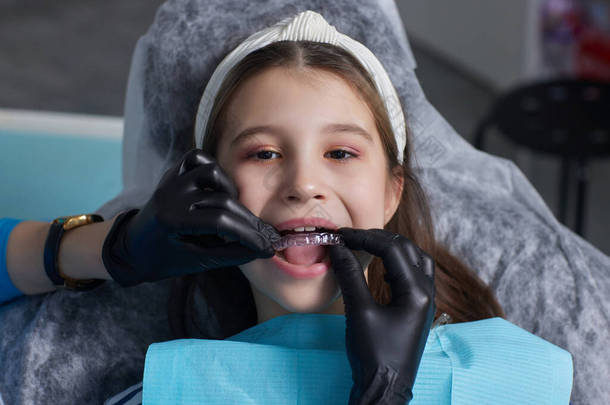 高加索小女孩看不见的假牙，指着她完美的直的牙齿。牙科保健和信心概念.