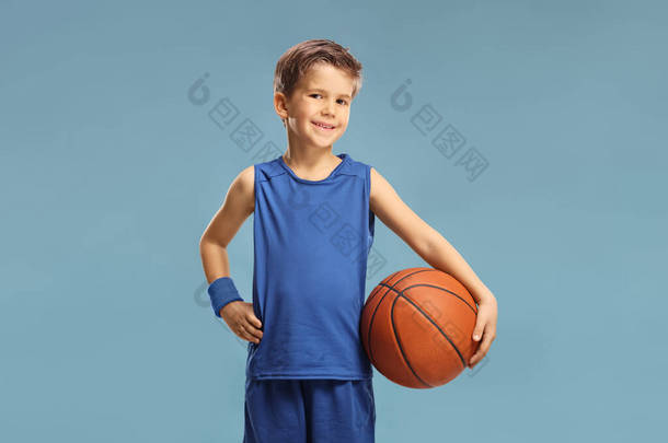 穿着蓝色球衣的男孩拿着一个蓝色背景的篮球